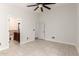 Spacious bedroom featuring tile flooring, neutral paint, a ceiling fan, and an en-suite bathroom at 4387 E Hartford Ave, Phoenix, AZ 85032