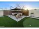 Outdoor seating area under a large umbrella, with turf putting green and stylish landscaping at 9013 E Shooting Star Dr, Gold Canyon, AZ 85118