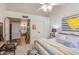 Bright bedroom featuring a ceiling fan, patterned accent wall art, and an ensuite bathroom at 9121 W Topeka Dr, Peoria, AZ 85382