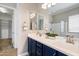 Bathroom featuring double sink vanity with blue cabinets, mirrors, and walk-in closet access at 16683 S 180Th Dr, Goodyear, AZ 85338