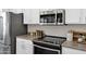 Modern kitchen with stainless steel microwave and range; featuring white cabinets and sleek black cooktop at 1120 S Valley Dr, Apache Junction, AZ 85120