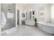 Bright bathroom featuring a glass enclosed shower, soaking tub, double vanity, and decorative wall art at 17690 E Bronco Dr, Queen Creek, AZ 85142