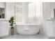 Bright bathroom with a soaking tub, decorative wall art, sheer curtains, and marble floors at 17690 E Bronco Dr, Queen Creek, AZ 85142