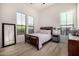 Bright bedroom features wood-look floors, a rustic wood bed frame and ample natural light from two large windows at 17690 E Bronco Dr, Queen Creek, AZ 85142