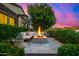 Inviting outdoor seating area with a modern fire pit, comfortable couch, and lush landscaping at 17690 E Bronco Dr, Queen Creek, AZ 85142