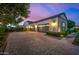 Three-car garage with brick driveway complemented by tidy landscaping and warm exterior lighting at 17690 E Bronco Dr, Queen Creek, AZ 85142