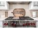 Close-up of a Wolf brand gas range with red knobs, tile backsplash, and custom range hood at 17690 E Bronco Dr, Queen Creek, AZ 85142