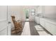 Bright laundry room featuring white cabinets, wood-look tile flooring and a rustic wood rocking chair at 17690 E Bronco Dr, Queen Creek, AZ 85142