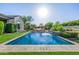 Backyard showcasing a pool with water feature, surrounded by lush greenery and complemented by stylish outdoor seating at 17690 E Bronco Dr, Queen Creek, AZ 85142