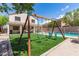 Beautiful backyard with a swing set, lush artificial grass, a pool, and mature trees at 23119 W Papago St, Buckeye, AZ 85326