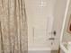 Clean white tiled shower with tub features neutral curtain for a simple yet functional design at 2358 E Peach Tree Dr, Chandler, AZ 85249