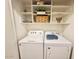 Bright laundry area with white washer, dryer, and shelving for organized storage solutions at 2358 E Peach Tree Dr, Chandler, AZ 85249