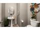 Compact powder room features a pedestal sink, modern decor, and a convenient toilet at 2418 W Jake Hvn, Phoenix, AZ 85085