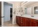 Bathroom featuring a double vanity with cherry wood cabinets and a view to the hall at 26529 N 167Th Ave, Surprise, AZ 85387