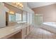 Bathroom features double sinks, a bathtub, walk-in shower, tile floors, and neutral walls at 5936 W Via Montoya Dr, Glendale, AZ 85310