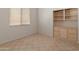 A bright bedroom features tile floor, built-in shelves, a window with blinds, and neutral paint color at 5936 W Via Montoya Dr, Glendale, AZ 85310