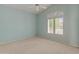 An empty bedroom with carpet and pale blue paint has a ceiling fan and bright shuttered window at 5936 W Via Montoya Dr, Glendale, AZ 85310