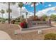 Community entrance sign with lush bougainvillea, palm trees, and decorative rock features at 5936 W Via Montoya Dr, Glendale, AZ 85310