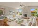 Bright living room with a white sofa, fireplace, and windows offering a view of the garden at 5936 W Via Montoya Dr, Glendale, AZ 85310