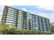 Modern high-rise condo building with glass facade and lush greenery on balconies and throughout the exterior at 7180 E Kierland Blvd # 1218, Scottsdale, AZ 85254