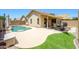 A spacious backyard featuring a pool, patio with sunshade, artificial turf and stone landscaping at 8331 E Plata Ave, Mesa, AZ 85212