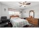 Bedroom with a window, ceiling fan, wood dresser, quilted bedspread, chair and small writing desk at 962 S Main Dr, Apache Junction, AZ 85120