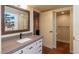 Bathroom vanity featuring a large mirror, modern countertop, stylish cabinets, and decorative door leading to toilet at 1302 E Nicolet Ave, Phoenix, AZ 85020