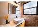 Well-lit bathroom showcasing a vessel sink, modern vanity, framed mirror, and an exposed brick accent wall at 1546 W Culver St, Phoenix, AZ 85007