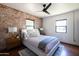 Serene bedroom featuring exposed brick wall, a ceiling fan, and a cozy, stylishly decorated bed with a blue accent at 1546 W Culver St, Phoenix, AZ 85007