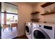 Well-lit laundry area featuring a washer, dryer, outdoor access, and decorative floating shelves for storage and decor at 1546 W Culver St, Phoenix, AZ 85007