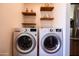Convenient laundry room equipped with a washer and dryer, complemented by floating shelves and a stainless steel refrigerator at 1546 W Culver St, Phoenix, AZ 85007