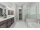 Bright bathroom featuring double sink vanity, white marble floors, glass-enclosed shower, and soaking tub at 18025 N 65Th Pl, Phoenix, AZ 85054