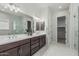 Bright bathroom featuring double sink vanity, white marble floors, and glass-enclosed shower and walk-in closet at 18025 N 65Th Pl, Phoenix, AZ 85054