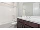 Bright bathroom featuring a shower over tub, dark vanity, and white counter at 18025 N 65Th Pl, Phoenix, AZ 85054