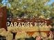 Rustic sign for Paradise Ridge community surrounded by desert landscaping and mature trees at 18025 N 65Th Pl, Phoenix, AZ 85054