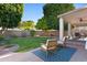 Serene backyard with covered patio, manicured lawn, mature trees, and seating area at 1975 E Chilton Dr, Tempe, AZ 85283