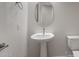 Bright bathroom features a pedestal sink, oval mirror, and a toilet with sleek fixtures at 22523 E Orchard Ln, Queen Creek, AZ 85142