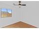 An empty bedroom featuring a ceiling fan, light hardwood flooring, and a window at 23077 S 214Th St, Queen Creek, AZ 85142