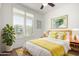 Bright bedroom featuring a bed with yellow accents, a ceiling fan, and a large window with bright, natural light at 3354 E Thornton Ave, Gilbert, AZ 85297