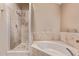 Bathroom showcasing a walk-in shower, soaking tub and beige travertine tile surround at 3505 E South Fork Dr, Phoenix, AZ 85044
