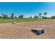 Spacious community area with manicured lawns and palm trees, featuring cornhole boards for outdoor fun on a clear day at 36480 W El Greco St, Maricopa, AZ 85138