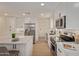 Well-lit kitchen showcasing white cabinets, stainless steel appliances, and a large island with a white countertop at 3826 W Davidson Ln, Phoenix, AZ 85051