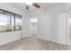Bright bedroom with light grey wood-look floors, ceiling fan, window, and walk-in closet at 5302 E Van Buren St # 2015, Phoenix, AZ 85008