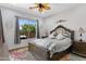 Bright bedroom features ceiling fan, window, and a wooden framed bed with decorative pillows and colorful floor rug at 5332 S Citrus Ct, Gilbert, AZ 85298