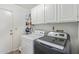Functional laundry room with a modern washer and dryer set, cabinetry, and shelving at 8020 W Windrose Dr, Peoria, AZ 85381