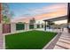 Beautiful backyard with green turf, covered patio, privacy wall, and sunset skies at 8117 E Lewis Ave, Scottsdale, AZ 85257