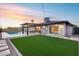 Backyard view showcasing turf, outdoor seating, and pool, illuminated by a setting sun at 8117 E Lewis Ave, Scottsdale, AZ 85257