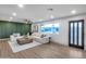 Bright living room featuring wood floors, stylish white sofa, a modern ceiling fan and a large window at 8117 E Lewis Ave, Scottsdale, AZ 85257