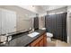 Well-lit bathroom featuring a granite countertop vanity, large mirror, and patterned shower curtain at 11840 N 59Th Ln, Glendale, AZ 85304