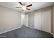 Bedroom with neutral walls and plush gray carpet, complemented by a ceiling fan, closet, and natural light at 11840 N 59Th Ln, Glendale, AZ 85304